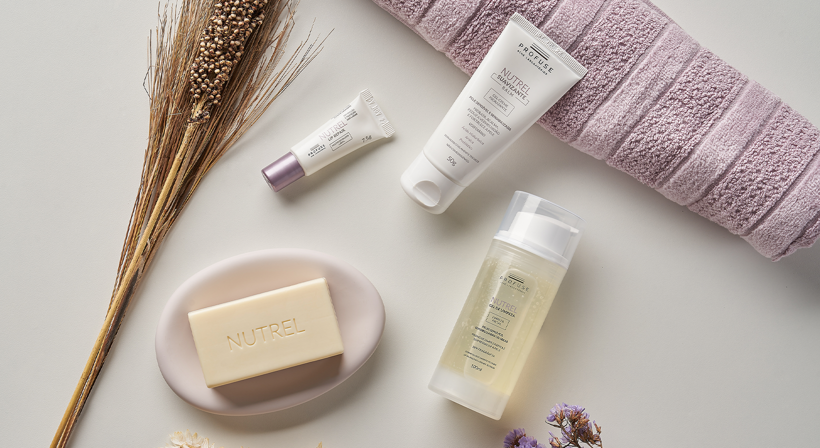 Imagem mostra os produtos da linha Nutrel deitados em uma superfície neutra com flores e uma toalha