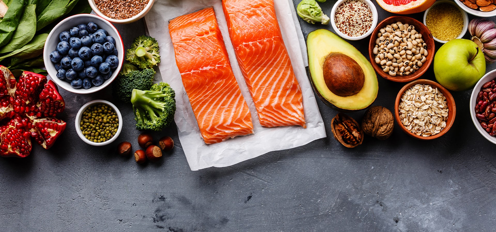 Bancada cinza escura com salmão, brócolis, abacate.